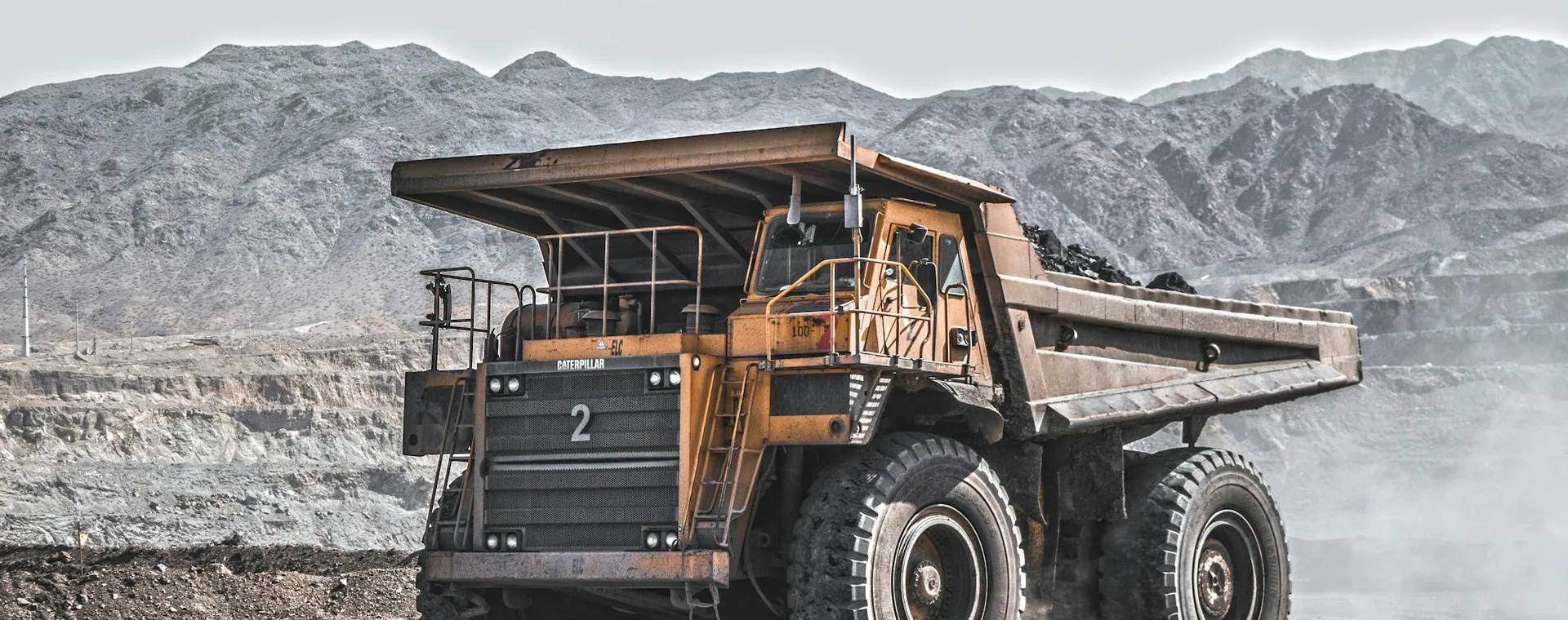 A haul truck on a mine road below rocky hills