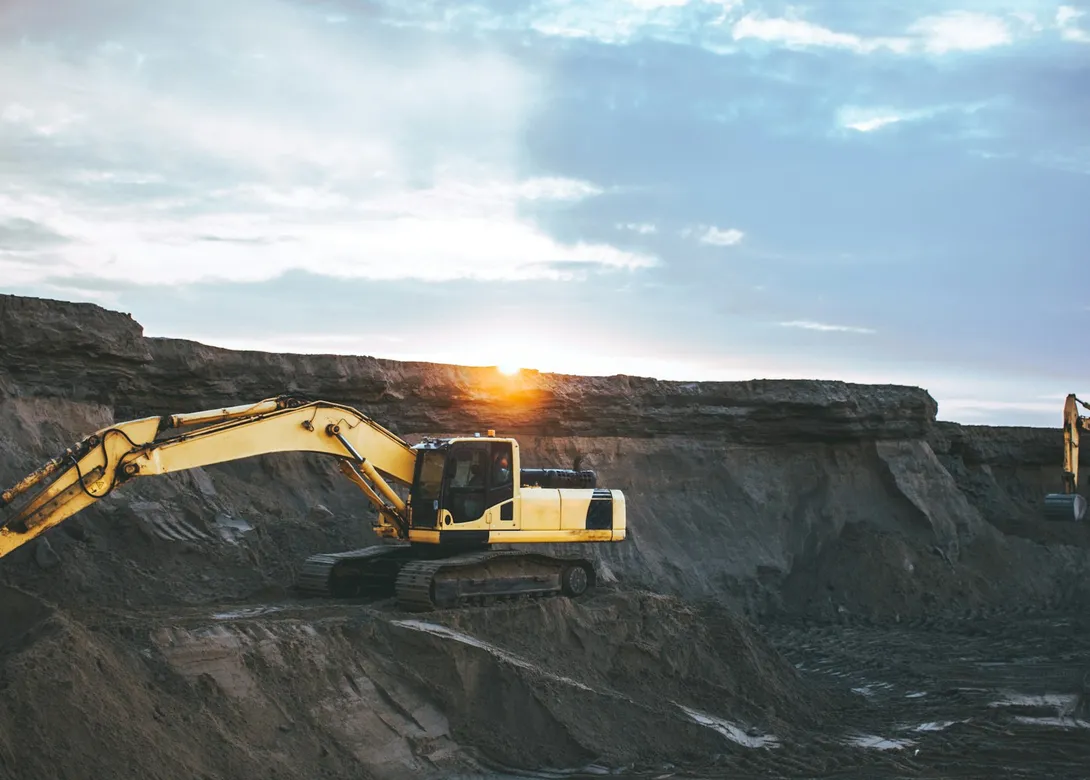 An excavator working a pit at sunset